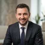 Профессиональный портрет уверенного российского бизнесмена с дружелюбным взглядом на размытом нейтральном фоне